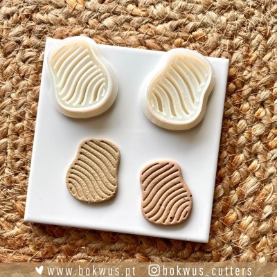 Cortadores de massinha ondulados brancos com peças de massinha beige e castanho claro