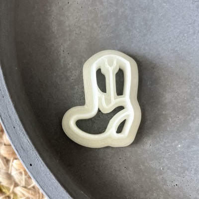 Cortador de biscoitos em forma de bota de cowboy em plástico branco numa tigela cinzenta