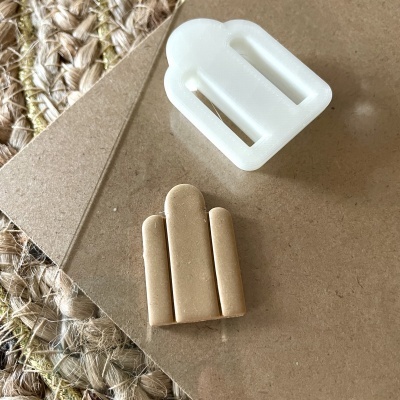 Molde branco de plástico e peça de argila bege sobre mesa castanha com esteira de fibra natural