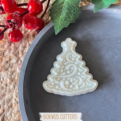 Cortador de bolachas em forma de árvore de Natal com decoração em prato cinza e decoração de folhas e bagas vermelhas