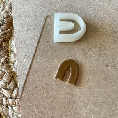 Dois moldes de silicone em formato de arcos, um branco e outro castanho, sobre superfície dura