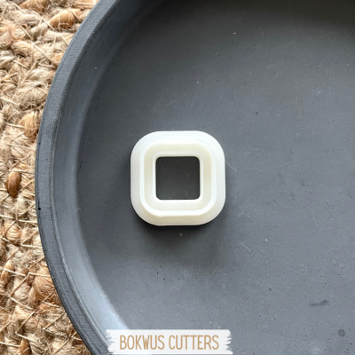 Cortador quadrado branco num prato preto com etiqueta BOKWUS CUTTERS