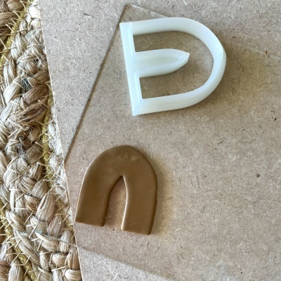 Molde castanho e objeto de silicone branco sobre superfície de madeira clara e tapete de fibra natural