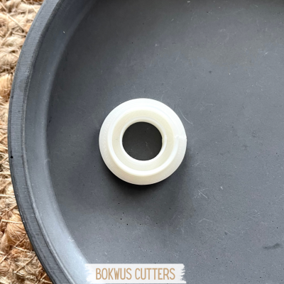 Rolo de fita adesiva branca sobre prato preto com texto BOKWUS CUTTERS