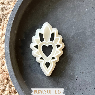 Cortador de biscoitos branco em forma de coração com padrão floral num prato preto