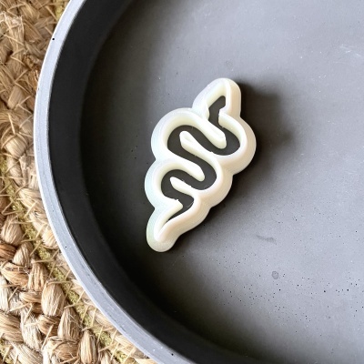 Objeto branco em forma de serpente numa superfície redonda cinza