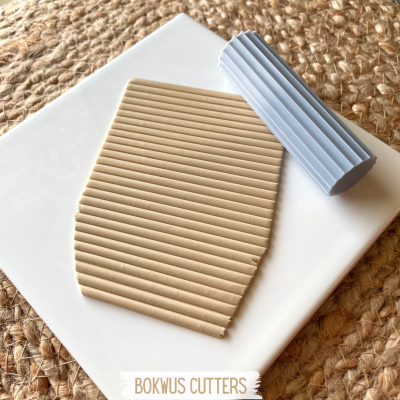 Dois cortadores de massa em silicone azul claro e bege, com padrões de ranhuras, sobre superfície branca