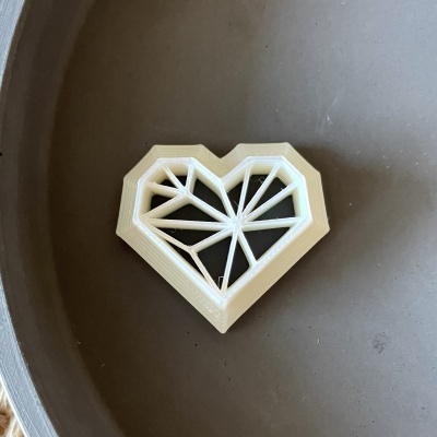 Objeto decorativo em forma de coração geométrico branco sobre superfície cinzenta