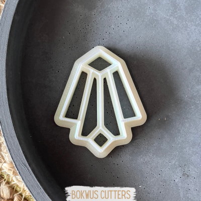 Cortador de bolachas branco com forma geométrica numa superfície cinzenta