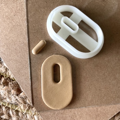 Molde plástico oval branco com peça de massa vermelha e pílula bege sobre cartão castanho