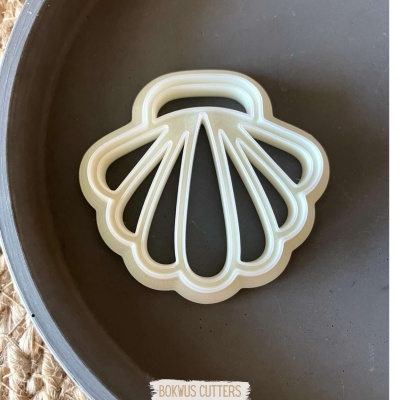 Cortador de biscoitos em forma de concha branco sobre prato cinzento