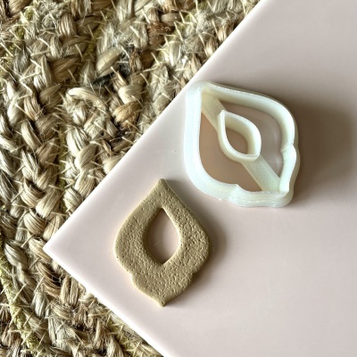 Cortador plástico branco em forma de folha com massa recortada à volta