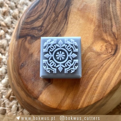 Carimbo quadrado cinzento com padrão branco em relevo sobre base de madeira