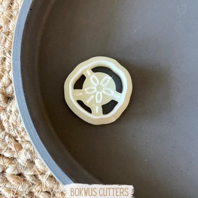 Cortador de massa branco em forma de roda numa superfície escura