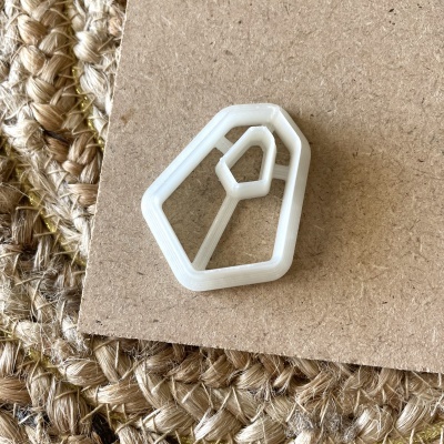 Prendedor branco geométrico em cartão com tapete de fios naturais trançados