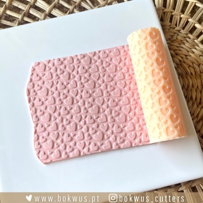 Rolinho texturizador com padrão de corações para fondant sobre prato branco