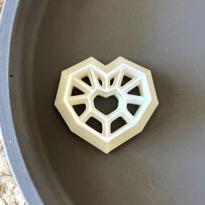 Objeto decorativo branco em forma de coração numa tigela cinza