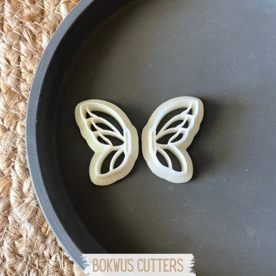 Dois cortadores de massa em forma de asas de borboleta brancas num prato cinzento