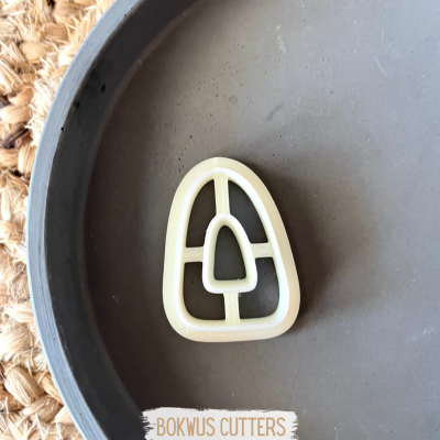 Forma cremosa para cortar biscoitos com design geométrico sobre bandeja cinza