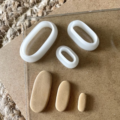 Seis objetos ovais brancos plásticos e bege madeira sobre cortiça e tapete de fibras