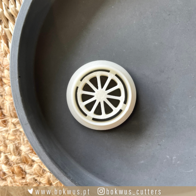 Cortador de massa branco com padrão de gomo de citrino num prato cinzento