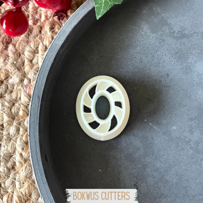 cortador de massa oval branco com padrão espiral dentro de prato cinza fosco