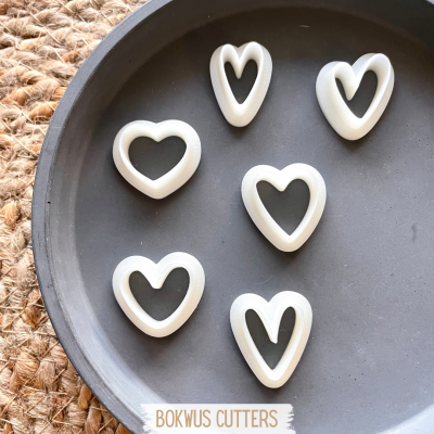 Cinco cortadores de coração brancos em prato preto com etiqueta BOKWUS CUTTERS.