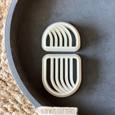 Formas em plástico branco com cortes curvos sobre superfície preta e tapete de juta