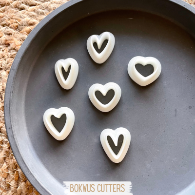 Seis cortadores de coração brancos numa bandeja preta com texto BOKWUS CUTTERS