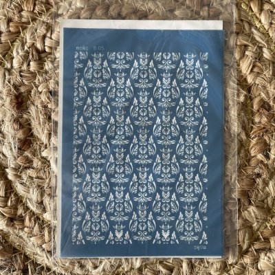 Cartão azul com padrão floral branco em embalagem plástica sobre superfície tecida castanha