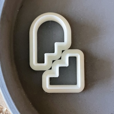 Dois cortadores de bolachas em forma de gelado brancos sobre um prato cinzento