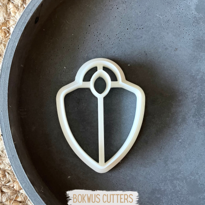 Cortador de bolachas em formato de escudo branco sobre fundo cinzento e palha