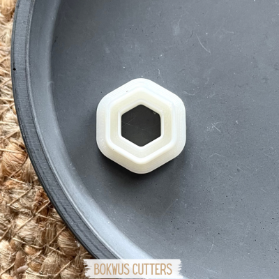 Cortante hexagonal branco sobre superfície preta curva