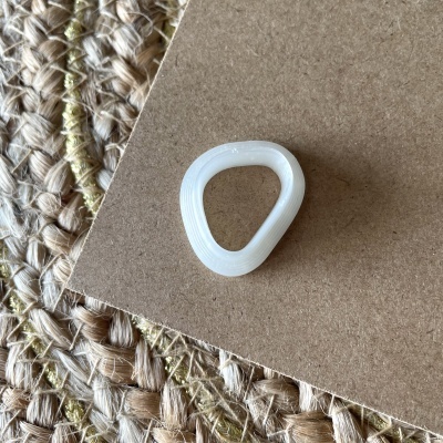 Anel plástico branco triangular sobre cartão e tapete de fibras naturais