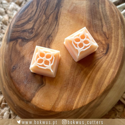 Dois objetos quadrados salmão claro com padrão em relevo sobre base de madeira