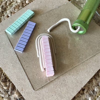 Peças retangulares coloridas e cilindro metálico verde com alça branca sobre base de madeira