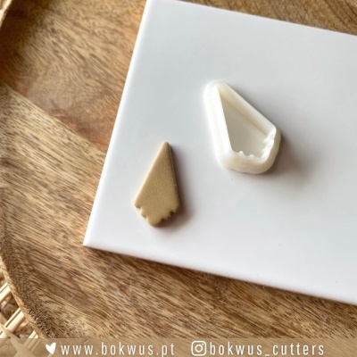 Cortante plástico branco formato triangular e fatia bolo bege num prato branco