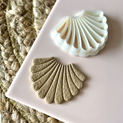 Dois objetos em formato de concha, um branco e um bege, em superfície rosa junto a tapete de fibras naturais