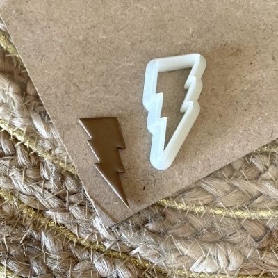 Moldes em formato de raio marrom metálico e branco plástico sobre papel castanho e tecido entrelaçado