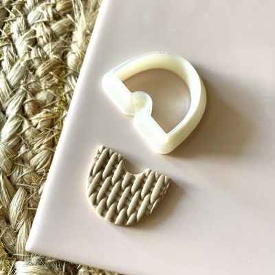 Cortador de biscoitos e massa com padrão entrelaçado sobre superfície rosa