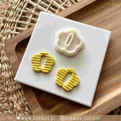 Três cortadores de massa flor e círculo sobre base branca e tabuleiro de madeira