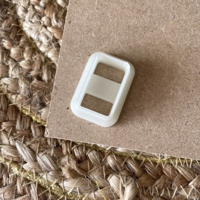 Trava de plástico branco retangular sobre cartão castanho e tecido natural trançado