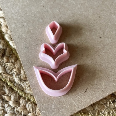 Conjunto de três cortadores de biscoitos florais cor-de-rosa sobre cartão castanho e tapete de palha