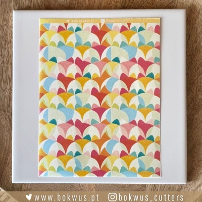 Base branca com folha decorativa colorida com padrão geométrico sobre superfície de madeira