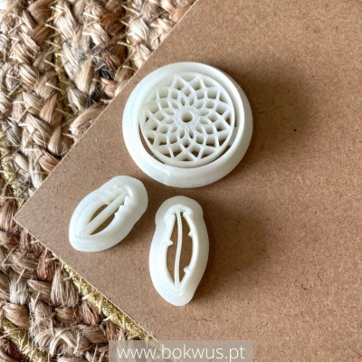 Três carimbos brancos com padrões florais e de folhas sobre cartão castanho