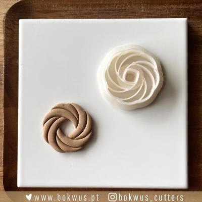 Dois cortadores de massa em forma de flor sobre placa branca com moldura de madeira