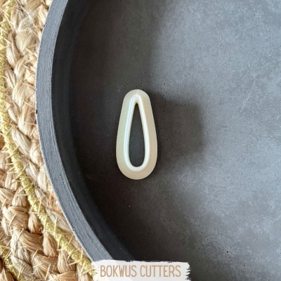 Acessório branco em forma de gota sobre superfície cinzenta redonda