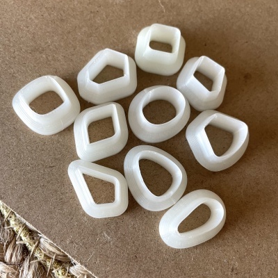 Dez peças brancas de plástico com formas geométricas variadas sobre superfície castanha