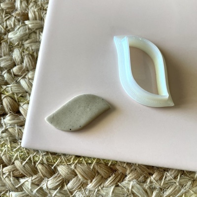 Peças em forma de folha sobre placa rosa clara em superfície de fibras naturais