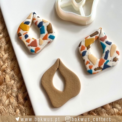 Figuras decorativas em forma de folhas com padrão terrazzo colorido e peça lisa castanha sobre base branca